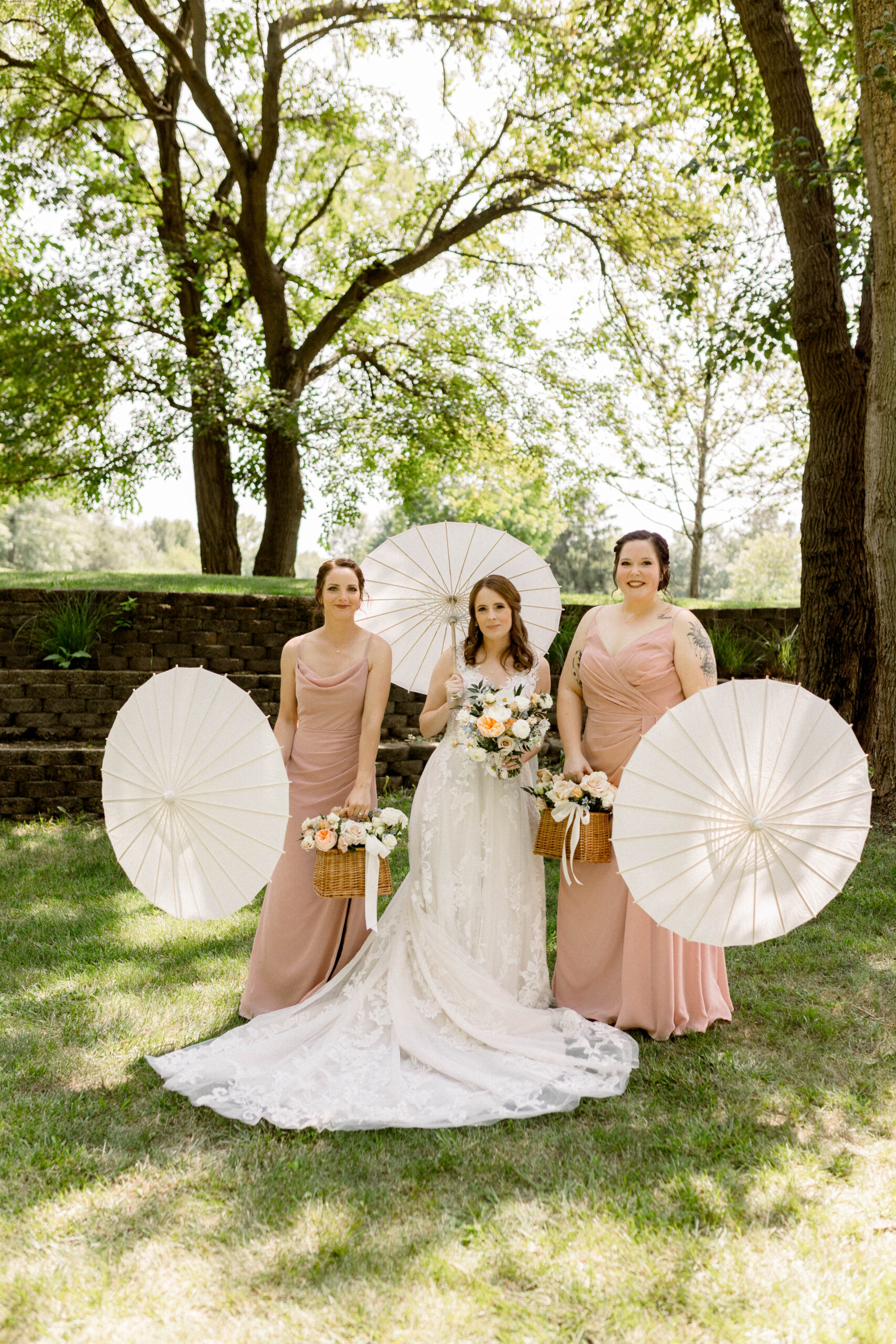 bride and bridesmaids posing with parasols at a summer outdoor wedding