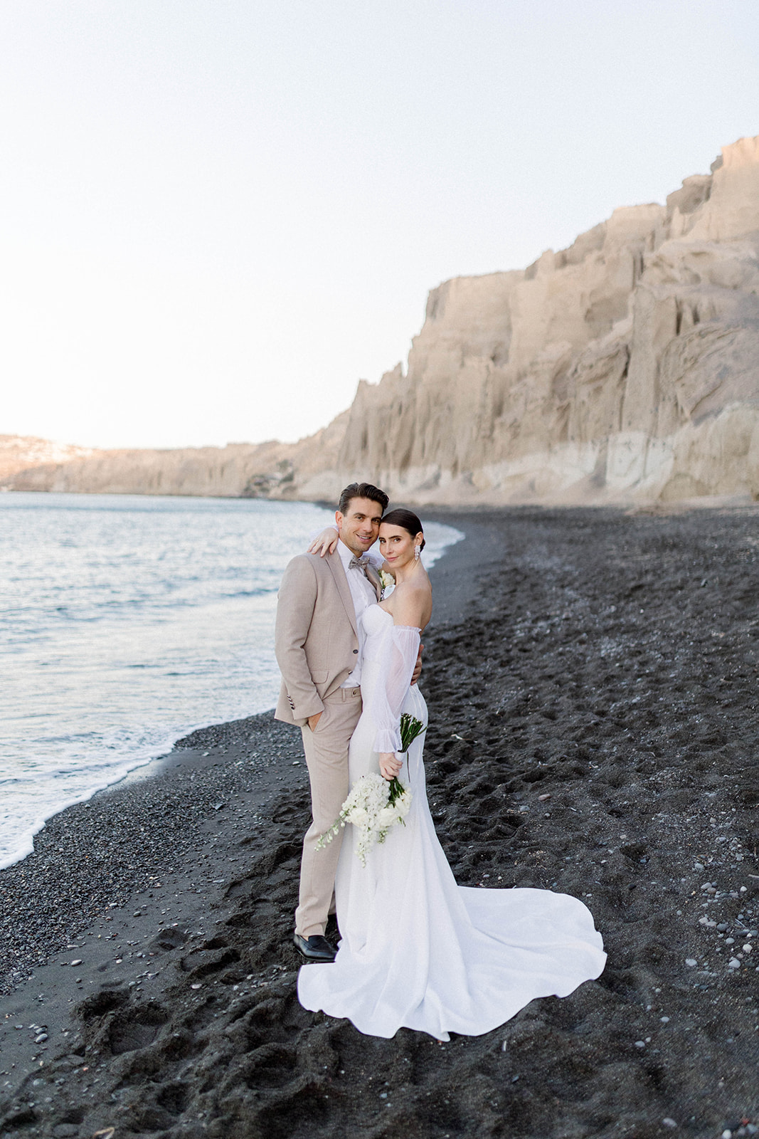 bride and groom on a Santorini black sand beach for a sunrise elopement